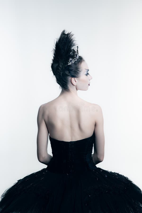 Back view of young ballerina wearing black tutu, stage dress posing  on white studio backgorund