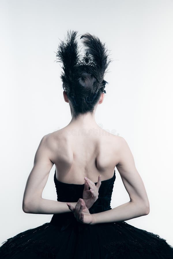 Back view of young ballerina wearing black tutu, stage dress posing  on white studio backgorund