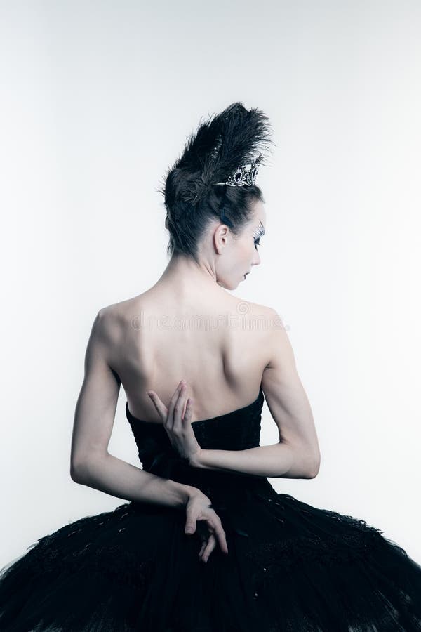 Back view of young ballerina wearing black tutu, stage dress posing  on white studio backgorund