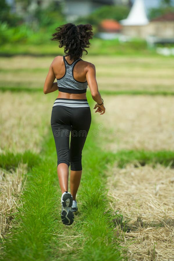 Back view of young runner woman with attractive and fit body in running outdoors workout at beautiful off road track green landsca stock photo Back view of young runner woman with attractive and fit body in running outdoors workout at beautiful off road track green landsca stock photo