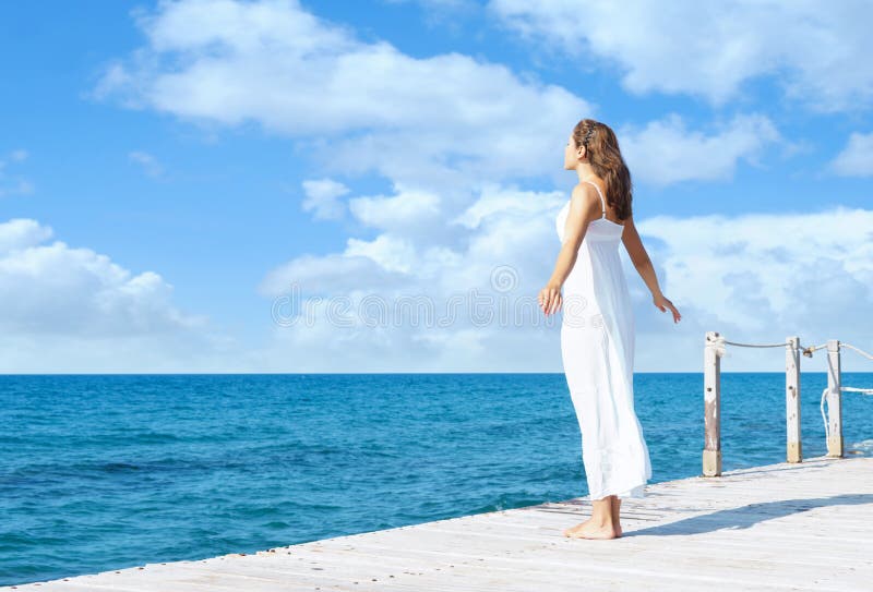 Back view of a young woman standing on a pier. Sea and sky back