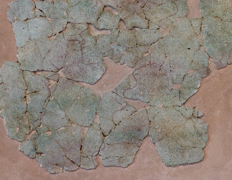 Dark cream stucco wall layered with multi toned pale green cracked stones