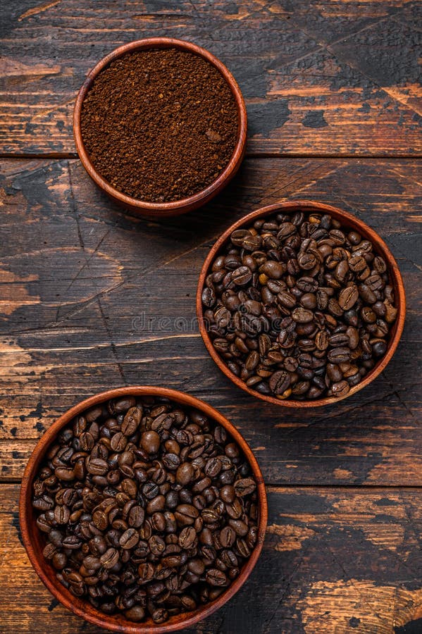 Ground Grinded Coffee in Glass Bowl with Roasted Coffee Beans on Dark