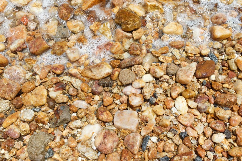 Background colorful wet stones on beach with water