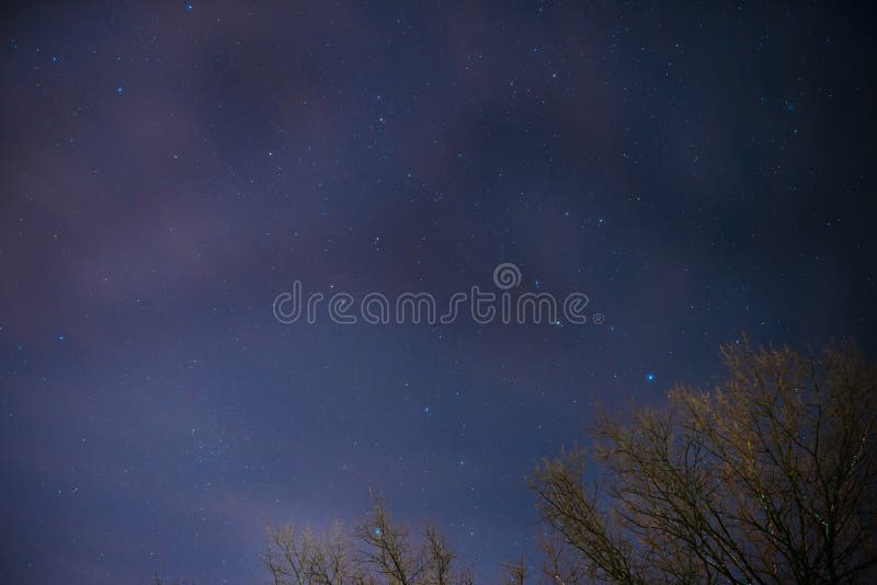 Background of dark-blue night sky with countless twinkle stars and moving white clouds upon on it