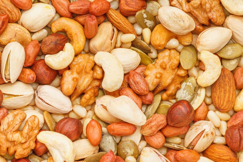 Background from different types of nuts and seeds - peeled walnut, hazelnuts, peeled peanut, pine nut kernels, almond seeds, cashew seeds, pistachio nuts in the shell, pumpkin seeds