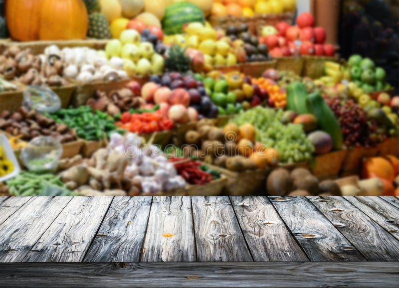 Background with empty wooden table and blured fruits and vegetables