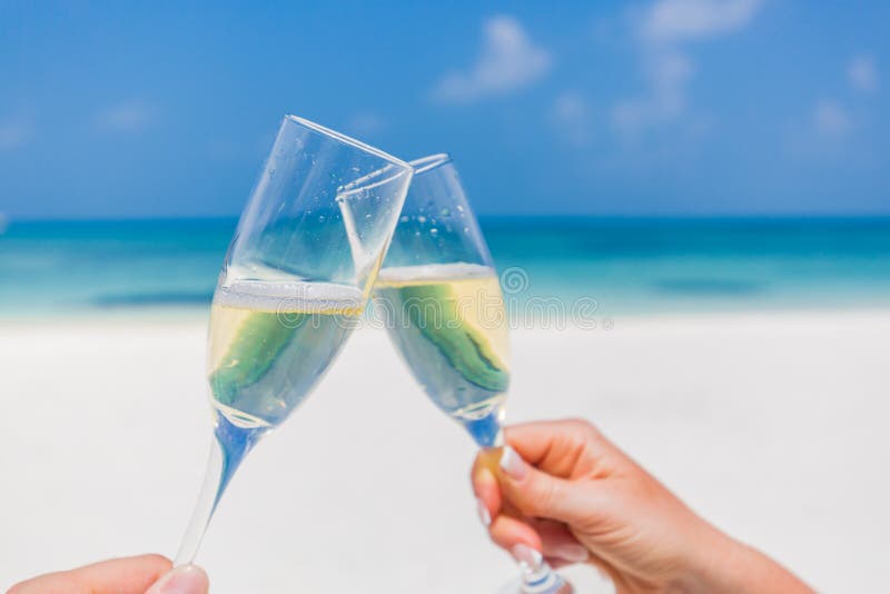 Champagne glasses in hands on beach background. Romantic honeymoon background