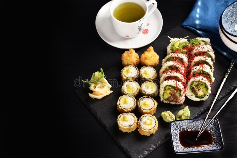 Background with Japanese Sushi Set and Green Tea on Black Board Stock