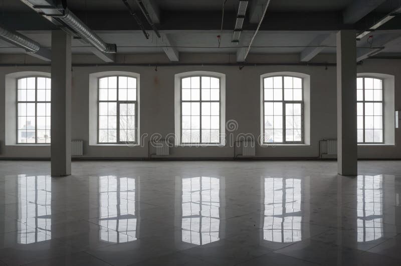 Empty large room in old factory building with row of big windows, columns and pipes under the beton ceiling