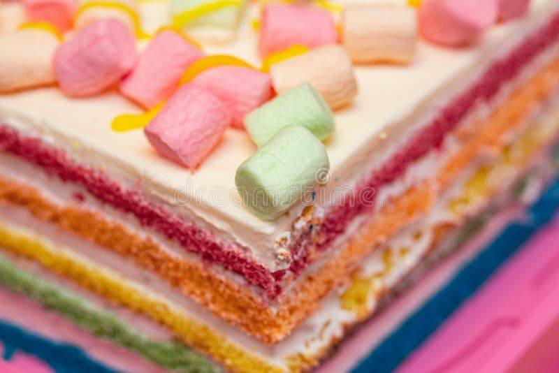 Background of multicolor four layer cake with colored marshmallow on the top. Close up. Rainbow cake texture stock images