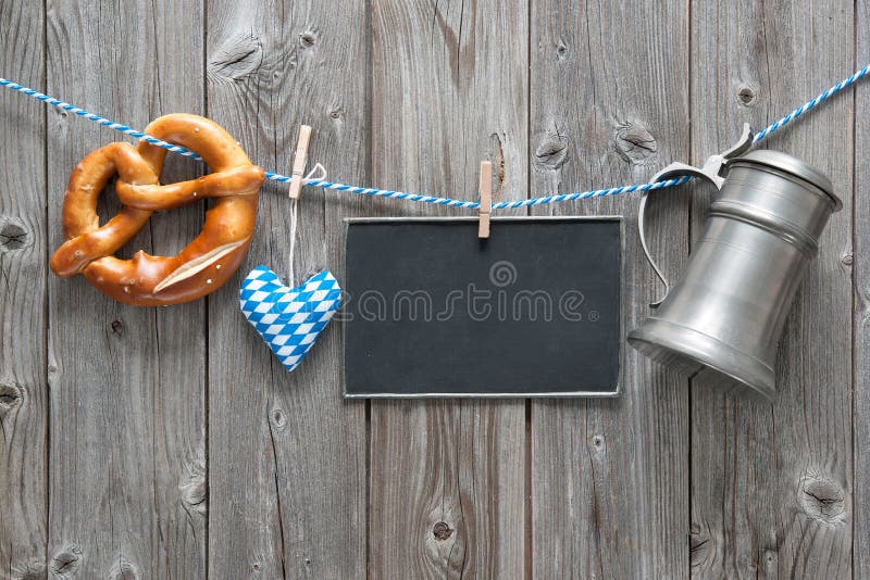 Message, beer mug and pretzel hanging on the clothesline against wooden board. Background for Oktoberfest