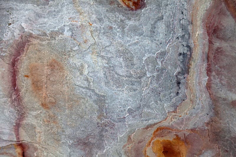 A rough stone pattern on the wall with iridescent yellow, beige, orange and gray. Design and architecture