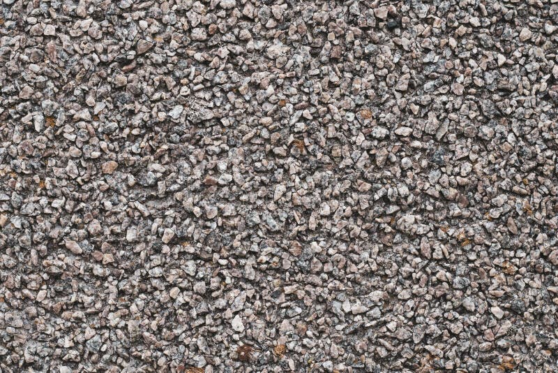 Background of small brown and gray pebbles. Rough stone wall, abstract pattern. Surface, rock texture. stock photo