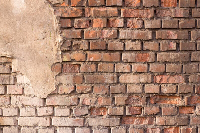 Background texture red old brick crumbling wall with a piece of crumbling plaster