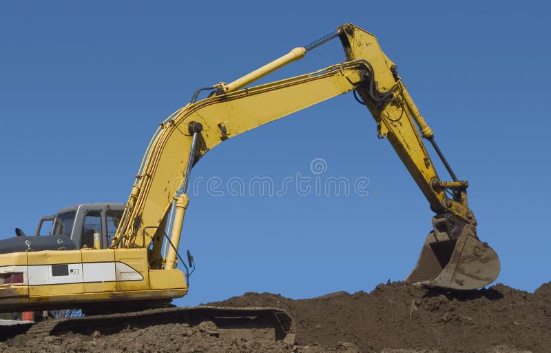 The claw of a backhoe works on a pile of dirt. Claw machine stock images, royalty-free photos and pictures