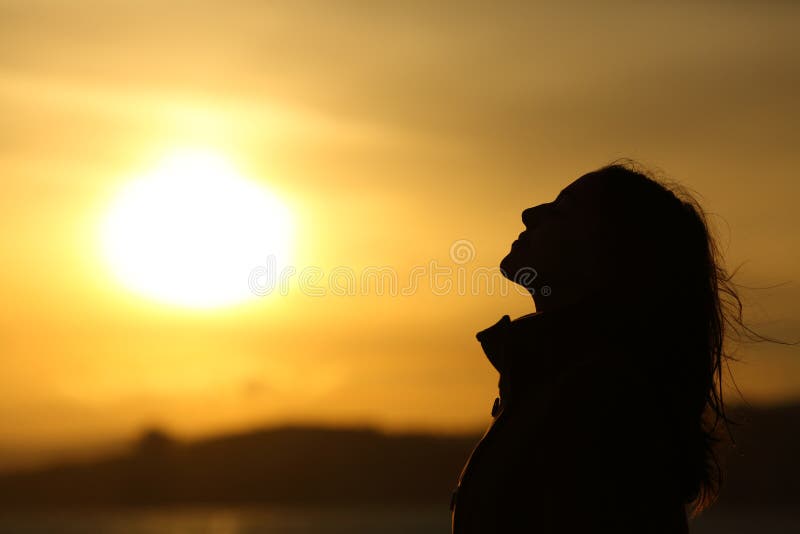 Side view backlight of woman silhouette breathing fresh air at sunset on the beach. Side view backlight of woman silhouette breathing fresh air at sunset on the beach