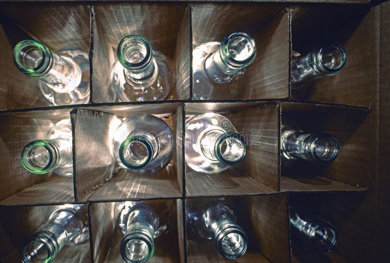 Backlighted backlit close shot of 12 a dozen assorted wine bottles with in a cardboard or paper case wine box against a white background with the light coming from behind lighting the bottles from below and beneath allowing the bottles to be almost silhouetted against the white creating a symmetrical arrangement. Cardboard color shapes stock images, royalty-free photos and pictures