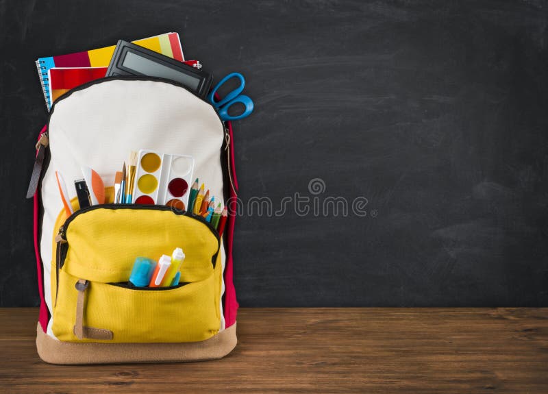 Backpack full of school supplies over black school board background stock photography