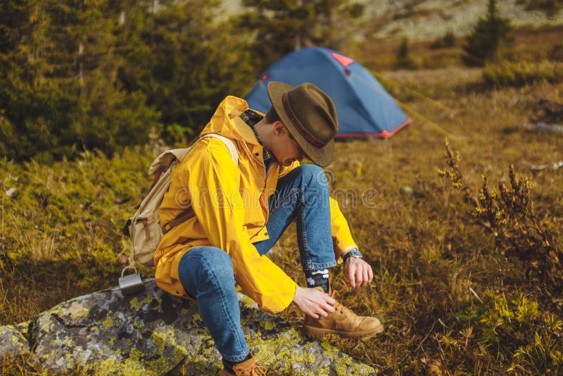 Backpacker in green hat, yellow coat laces shoes royalty free stock images Backpacker in green hat, yellow coat laces shoes royalty free stock images