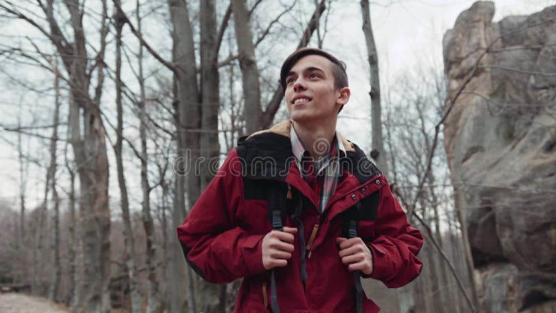 Backpacker joven que camina a través del bosque abandonado, feliz sonriendo y observando el paisaje Estación del otoño, caida