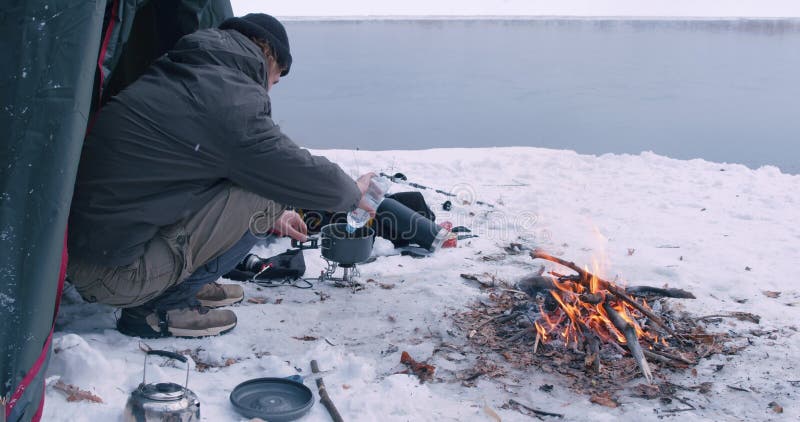 Backpacker preparing camp food outdoors, guy pouring clear water into the pan stock footage