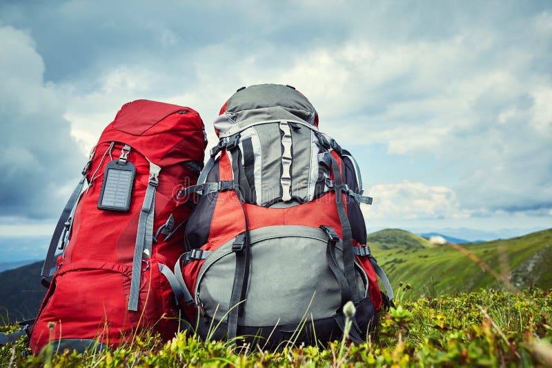 Backpacks in the Mountains Overlooking the Mountains on the Green Grass