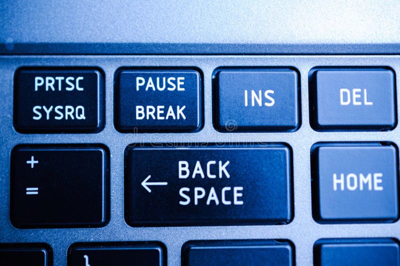 Backspace button on the keyboard closeup surrounded with Print Screen, Pause Breack, Insert , Home and other buttons in blue color cast