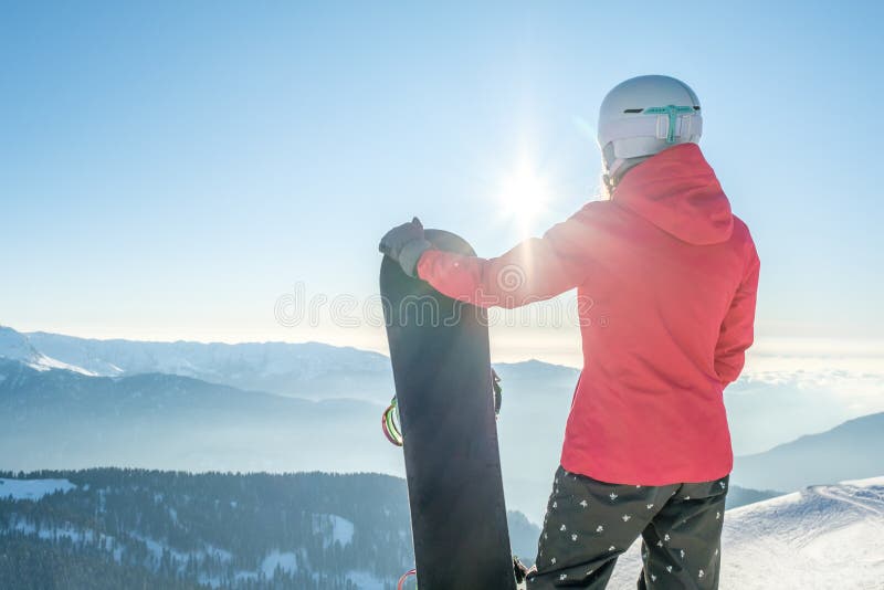 Backvy för kvinnliga snöspolare som står med snöpapp och som njuter av bergslandskap royaltyfria foton