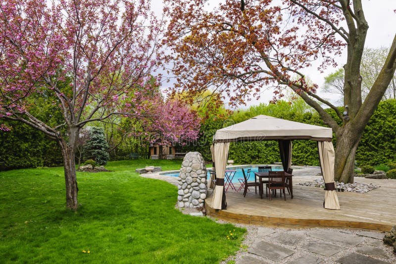 Backyard with gazebo and deck. Residential backyard with gazebo, deck, stone patio and swimming pool stock photo