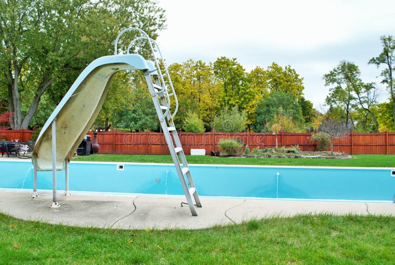 Backyard swimming pool with pool slide emptied out shutting down for winter royalty free stock photography
