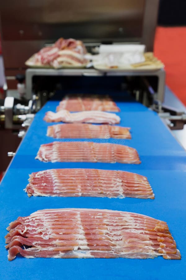 bacons slicing on the conveyor belt of meat slicing machinery industrial ready to fill in the packaging of meat product at the food factory. bacons slicing on the conveyor belt of meat slicing machinery industrial ready to fill in the packaging of meat product at the food factory