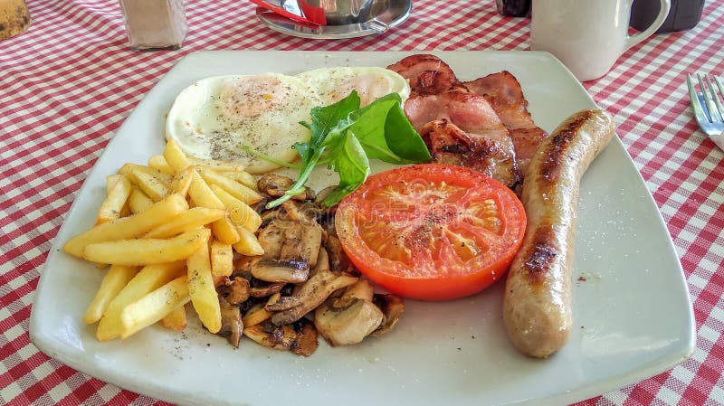 Bacon och ägg frukosterar med tomaten, korven, chiper och champinjoner royaltyfria foton Bacon och ägg frukosterar med tomaten, korven, chiper och champinjoner royaltyfria foton