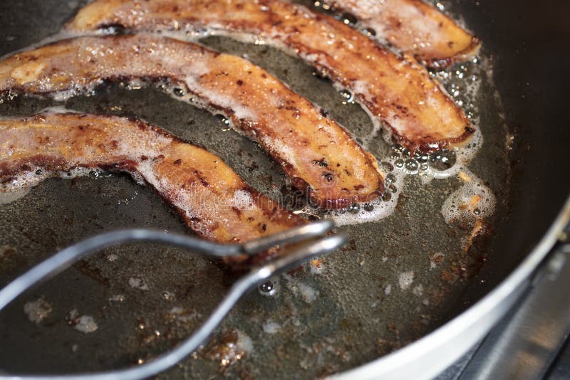 Bacon a fritar numa frigideira grande imagens de stock