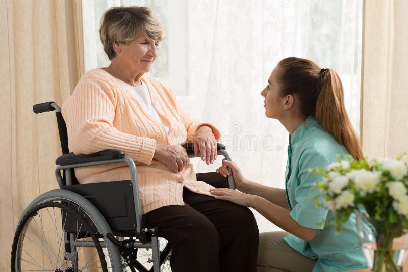 Picture of caregiver helping old female on wheelchair. Picture of caregiver helping old female on wheelchair