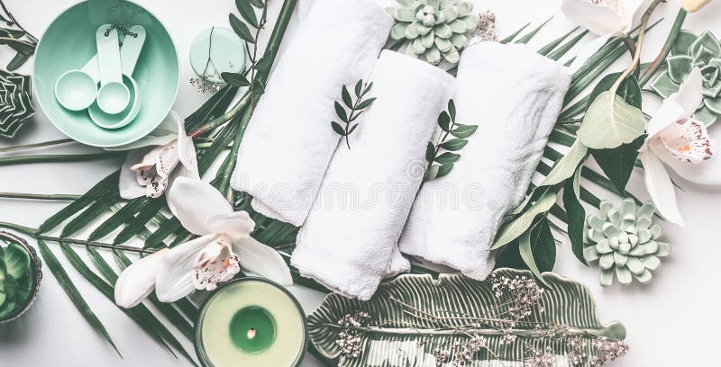 Badekureinstellung mit Tüchern, grüne Kerze, tropische Blätter, weiße Orchidee blüht, Draufsicht stockfoto