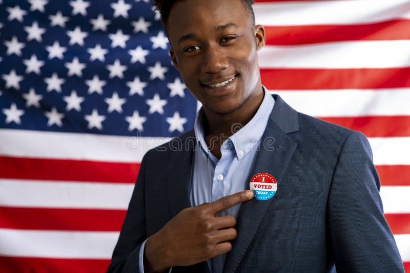 Badge US Election 2020 on suit of african american businessman, American flag background. Badge US Election 2020 on suit of african american businessman, American flag background