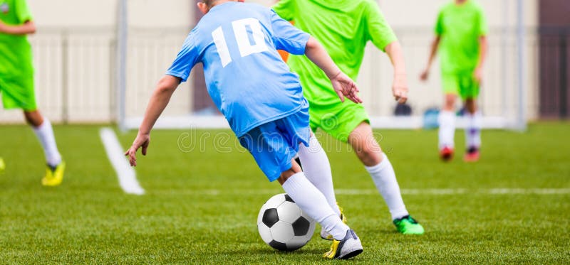 Badine le match de football Garçons donnant un coup de pied la boule du football sur le champ de sports photo libre de droits Badine le match de football Garçons donnant un coup de pied la boule du football sur le champ de sports photo libre de droits