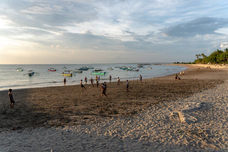 BADUNG BALI/INDONESIA-APRIL 02 2019: Asiatisk tonåringlekfotboll eller fotboll på stranden med solnedgång eller guld- timmar bakg arkivbilder BADUNG BALI/INDONESIA-APRIL 02 2019: Asiatisk tonåringlekfotboll eller fotboll på stranden med solnedgång eller guld- timmar bakg arkivbilder