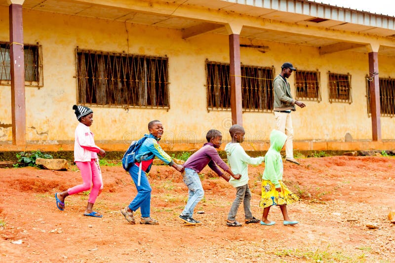Bafoussam, Cameroon - 06 august 2018: young smiling african pupils playig and having fun outside poor village school during summer royalty free stock photography Bafoussam, Cameroon - 06 august 2018: young smiling african pupils playig and having fun outside poor village school during summer royalty free stock photography