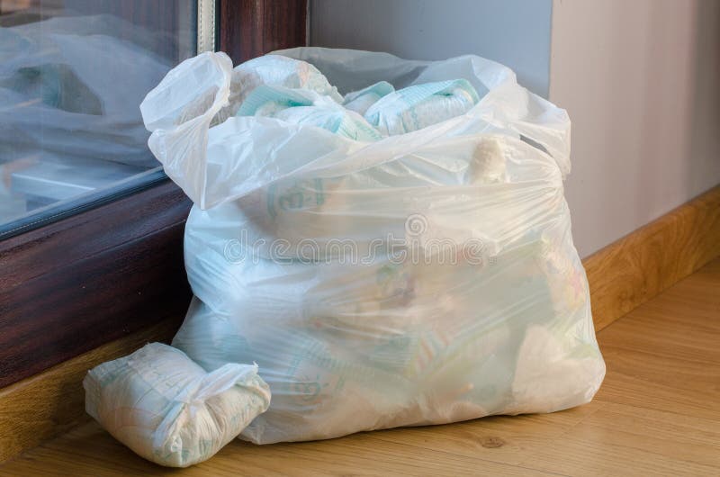 A bag full of dirty baby`s diapers standing on the floor stock images.