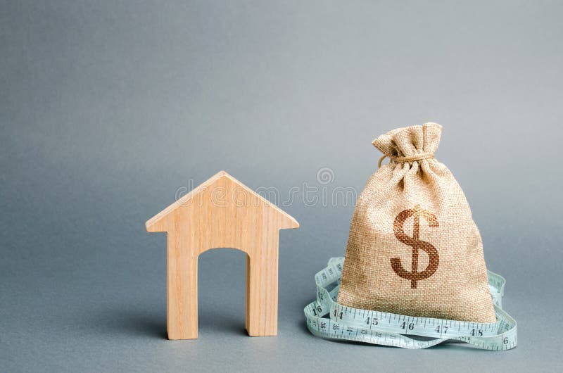 Bag with money and tape measure with a wooden house. The concept of a limited real estate budget. Low subsidies. Lack of royalty free stock photos Bag with money and tape measure with a wooden house. The concept of a limited real estate budget. Low subsidies. Lack of royalty free stock photos