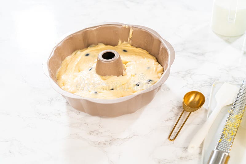 Delicately transferring the cake batter into the pre-greased bundt cake pan, setting the stage for a successful baking process. Delicately transferring the cake batter into the pre-greased bundt cake pan, setting the stage for a successful baking process.