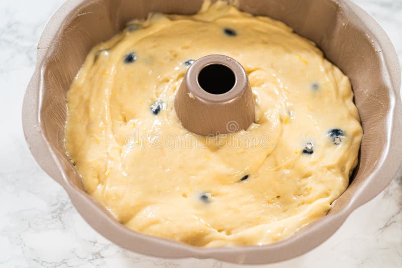 Delicately transferring the cake batter into the pre-greased bundt cake pan, setting the stage for a successful baking process. Delicately transferring the cake batter into the pre-greased bundt cake pan, setting the stage for a successful baking process.