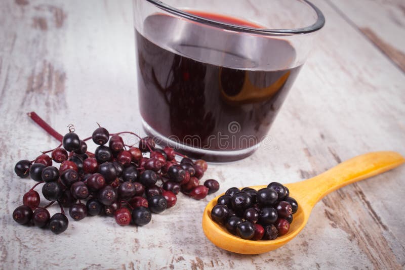 Baga de sabugueiro fresca com colher e suco de madeira no fundo de madeira velho, nutrição saudável imagem de stock royalty free Baga de sabugueiro fresca com colher e suco de madeira no fundo de madeira velho, nutrição saudável imagem de stock royalty free