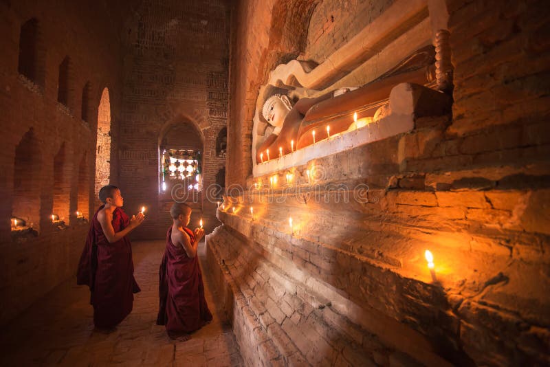 BAGAN,MYANMAR; DEC 11; Two monk of Buddha praying statue of Buddha by candle burning on December 11,2015 in Ancient temple Bagan , Myanmar