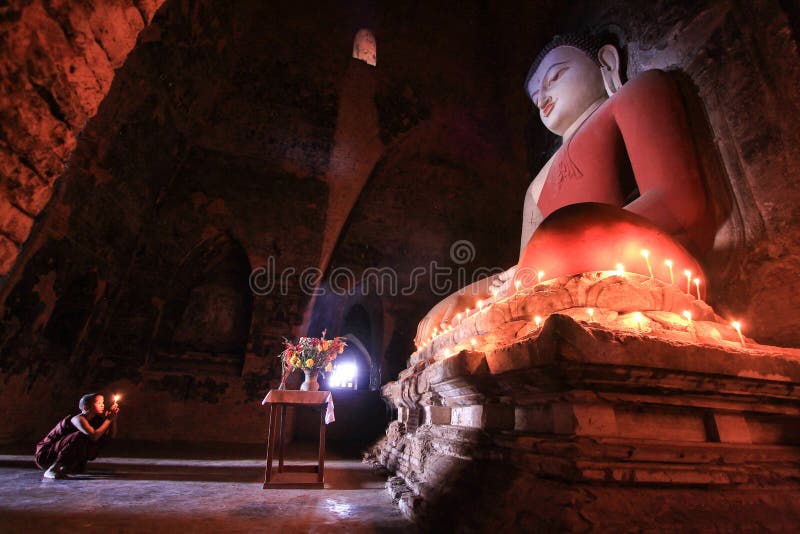 BAGAN, MYANMAR - mai 2016 : Bougies brûlantes de moine devant la statue de Bouddha à l'intérieur de la pagoda en mai 2016 dans Ba images libres de droits BAGAN, MYANMAR - mai 2016 : Bougies brûlantes de moine devant la statue de Bouddha à l'intérieur de la pagoda en mai 2016 dans Ba images libres de droits