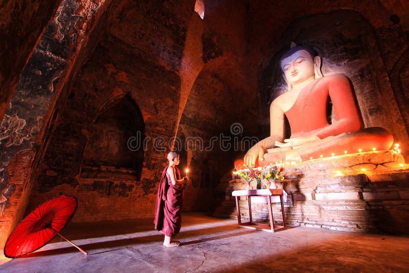 BAGAN, MYANMAR - mayo de 2016: Velas ardientes del monje delante de la estatua de Buda dentro de la pagoda en mayo de 2016 en Bag imagenes de archivo BAGAN, MYANMAR - mayo de 2016: Velas ardientes del monje delante de la estatua de Buda dentro de la pagoda en mayo de 2016 en Bag imagenes de archivo