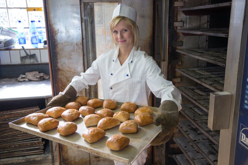 Baker putting a tablet of buns or bread into an oven. Baker putting a tablet of buns or bread into an oven