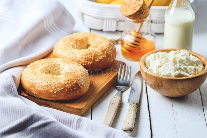 Bagel mit Hüttenkäse, Banane und Honig Konzept des weißen hölzernen Hintergrundes des gesunden Frühstücks stockfotografie Bagel mit Hüttenkäse, Banane und Honig Konzept des weißen hölzernen Hintergrundes des gesunden Frühstücks stockfotografie